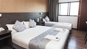 A hotel room with two beds, a nightstand with a phone, a headboard, and a window with curtains. - Hotel Kapital (Maputo)