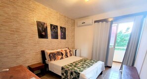 Una habitación de hotel con una cama, una mesita de noche, un banco de madera, una pared con textura y una ventana con cortinas.