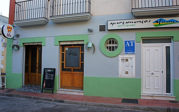 A building with a green and white facade, a sign for 'Alhambra La Seca', and a door labeled 'AT'. - Apartamentos Turísticos Albanta (Alhama de Almeria)