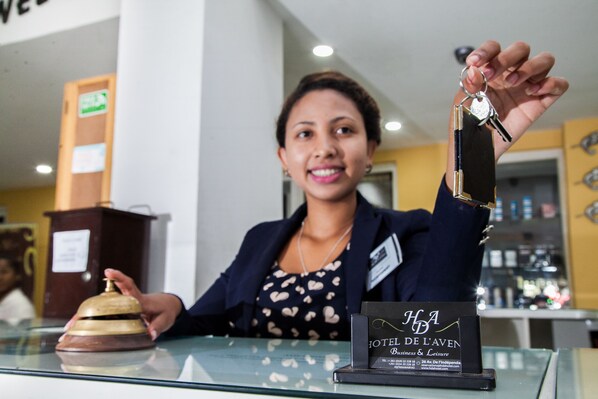 A hotel reception desk with a bell, a name tag, and a sign for Hotel de l'Aven.