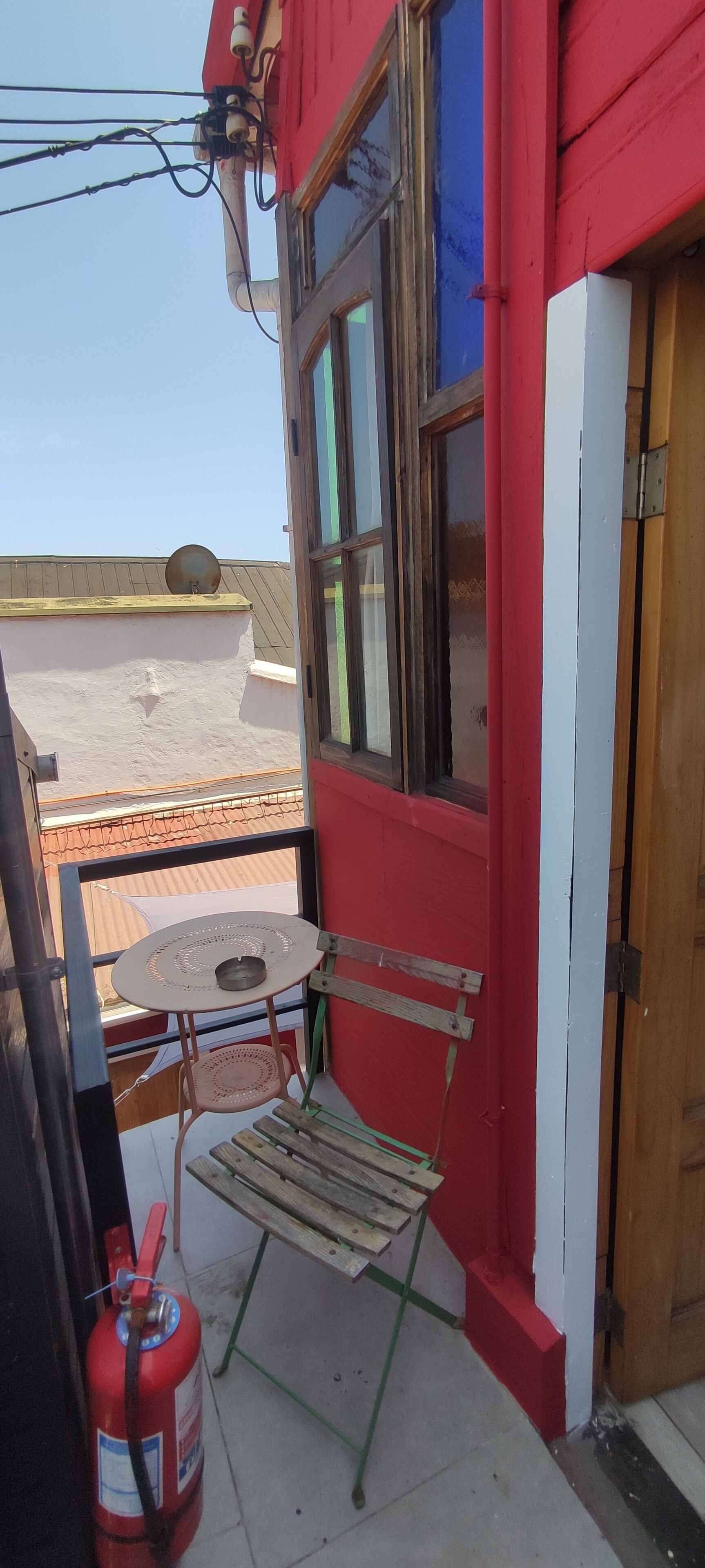 A red and white building with a window, a table, and a chair outside.