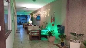 A hallway with a tiled floor, a fire extinguisher, potted plants, and a string of lights. - Pousada do Marinho (Búzios)