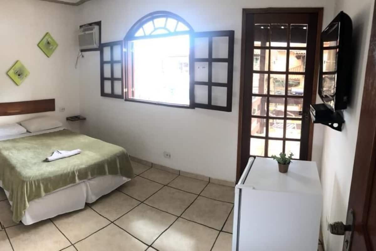 A bedroom with a bed, a wardrobe, a window, and a television.
