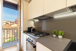 A modern kitchen with a gas stove, a coffee maker, and two potted plants. - Luxury Apartment On Grand Canal by Wonderful Italy (Venice)