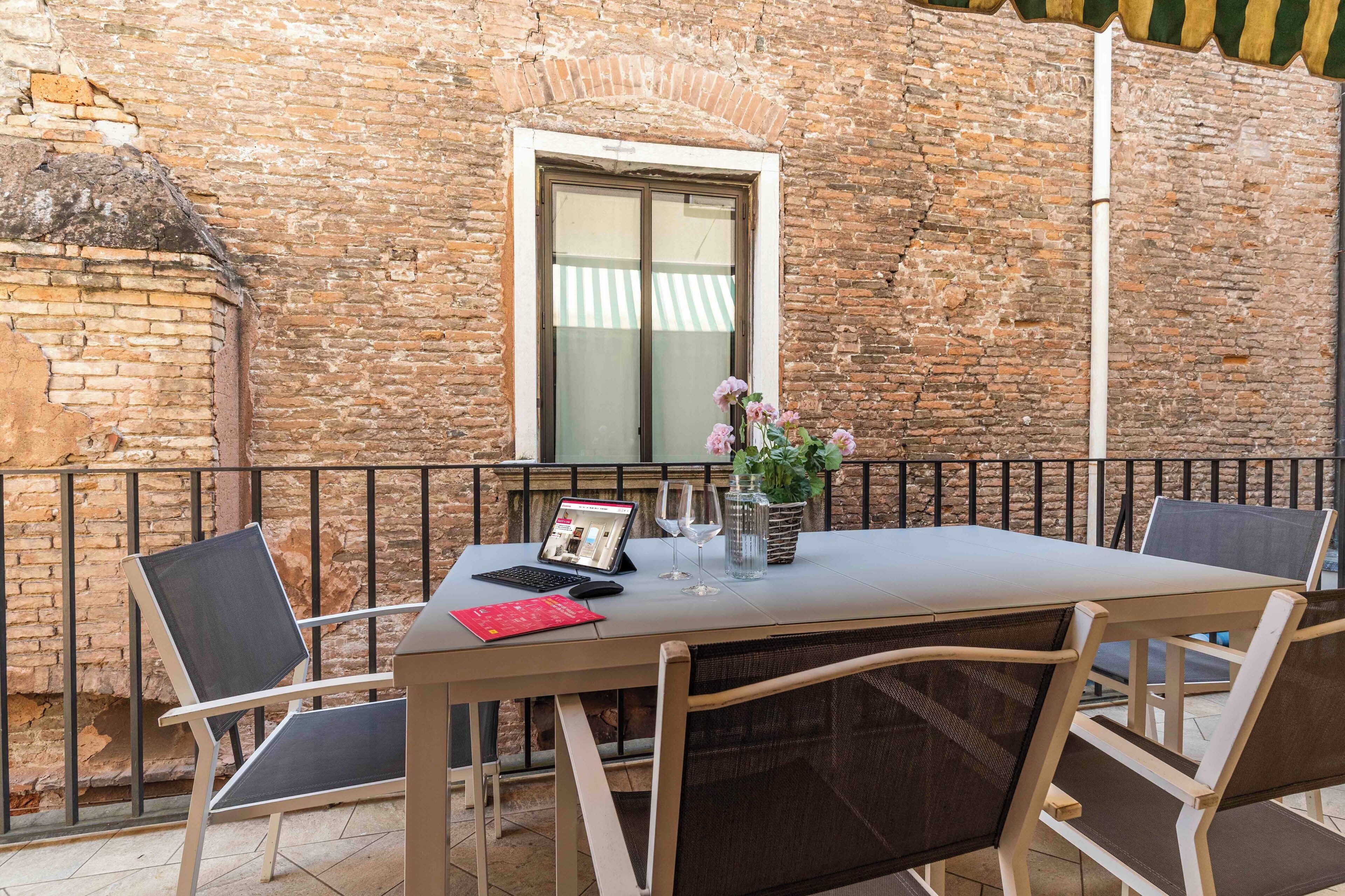 Un espacio al aire libre con una mesa, sillas y una computadora portátil.