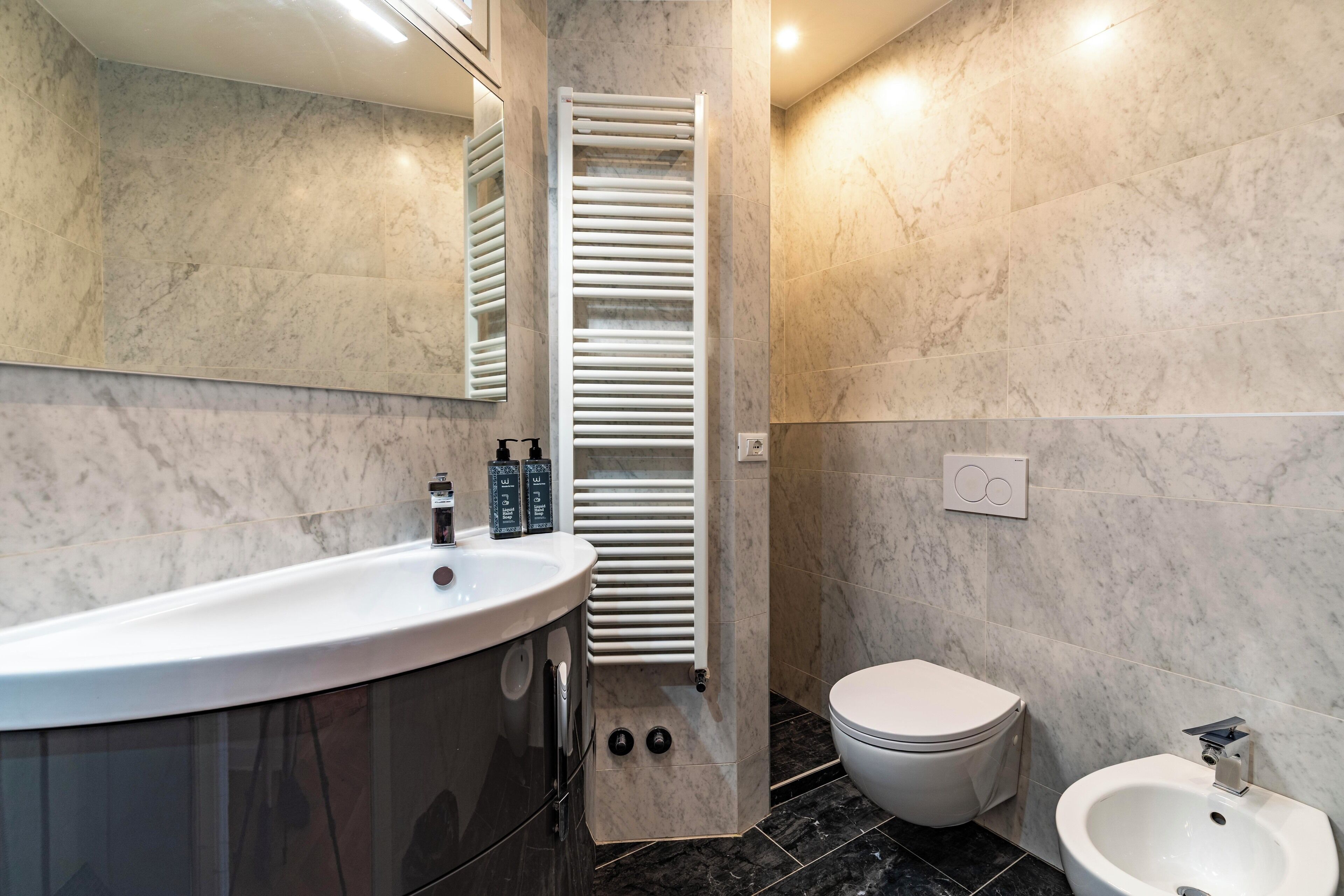 A modern bathroom with a white sink, a toilet, and a bidet.