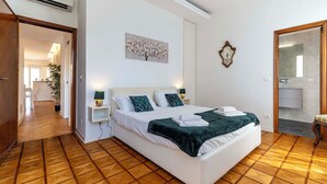Een hotelkamer met een groot bed, een nachtkastje, een spiegel en een schilderij aan de muur.