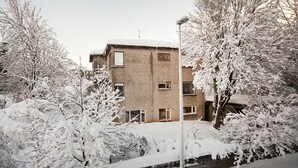 Een meerhoog gebouw met een bakstenen gevel, omringd door met sneeuw bedekte bomen en een besneeuwde grond.
