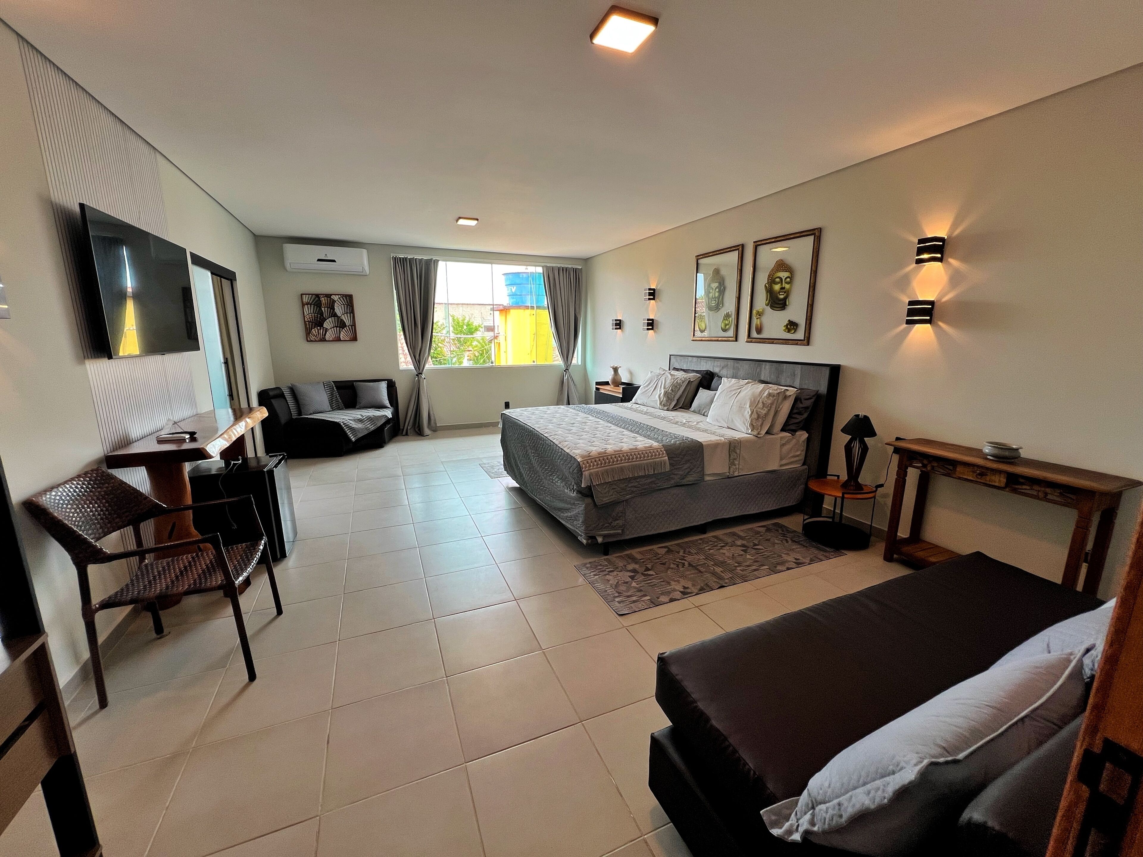 A modern hotel room with a bed, desk, chair, and a TV.