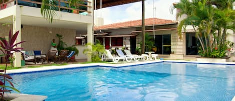 Una piscina al aire libre, sillones reclinables de piscina