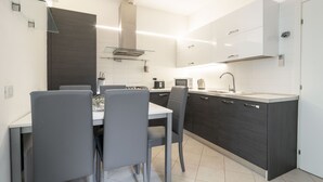 Una cucina moderna con isola centrale, mobili scuri e piano di lavoro bianco.