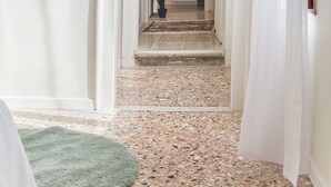 Un corridoio con una porta bianca, una pianta in vaso e un termosifone sullo sfondo.