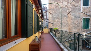 Un balcone stretto con una panchina in legno, una pianta in vaso e una ringhiera in metallo.
