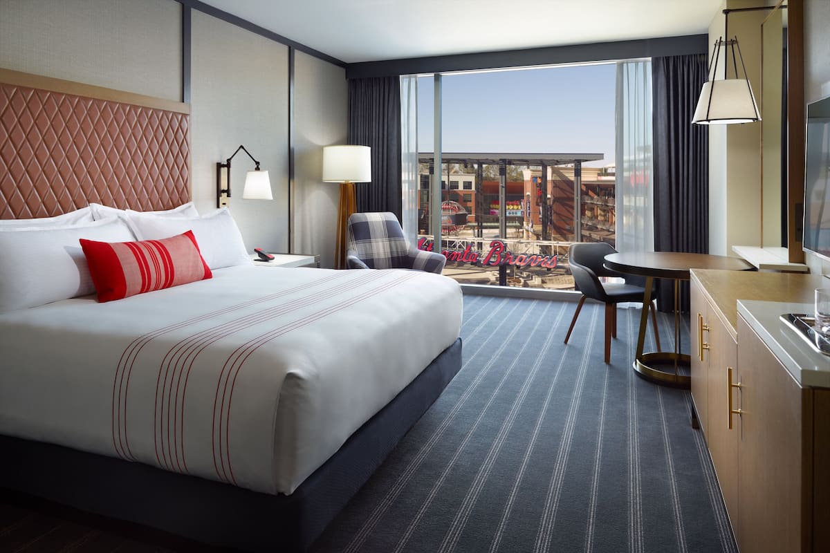 Une chambre d’hôtel avec un grand lit, un bureau, une chaise et une vue sur la ville.