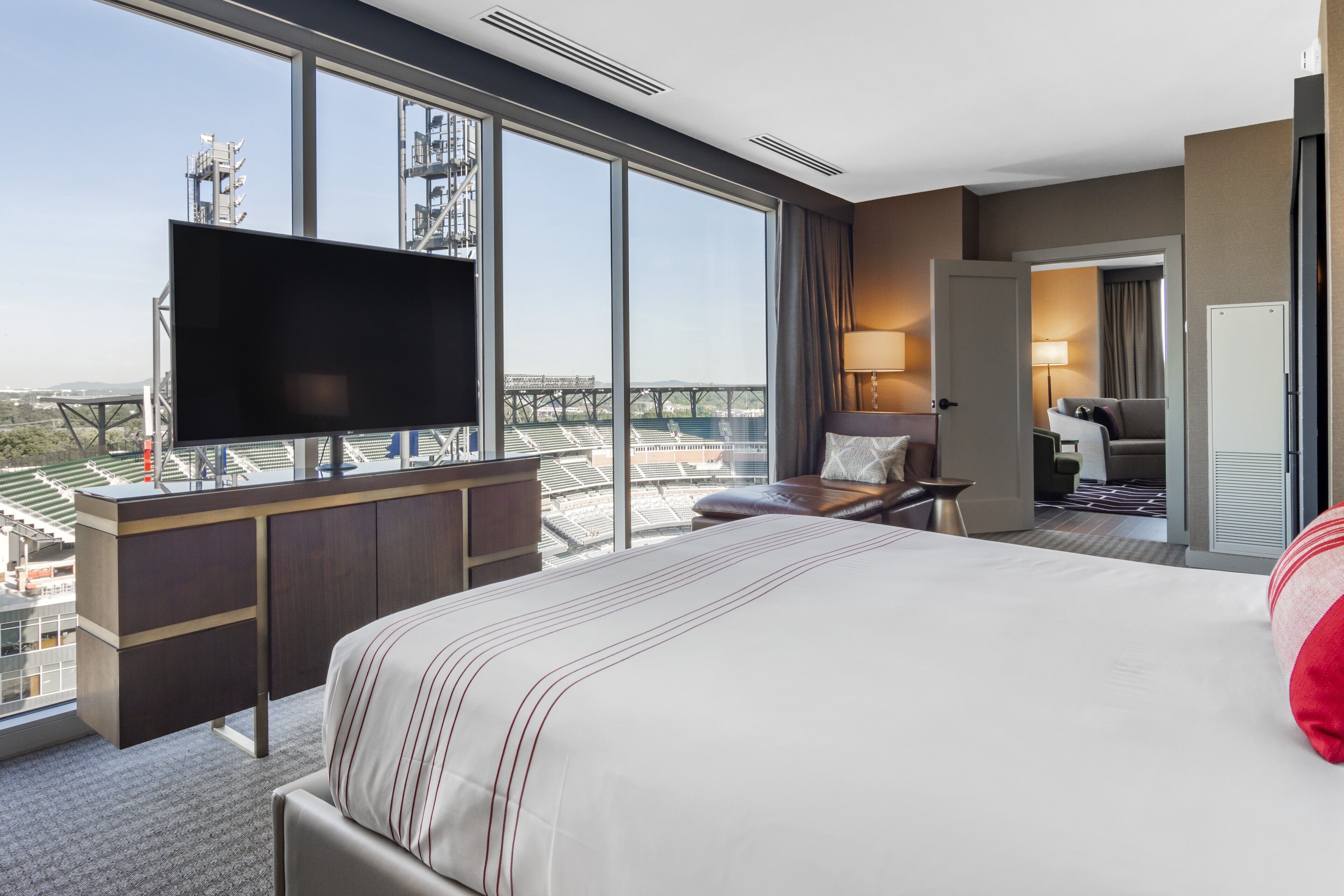 A hotel room with a large bed, a TV on a desk, a view of a bridge, and a door leading to a bathroom.