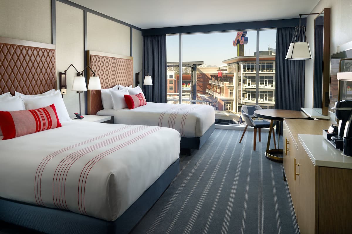 Une chambre d’hôtel avec deux lits, un bureau et une vue sur la ville.