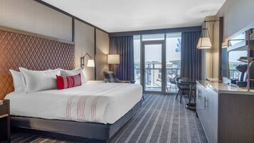 Habitación de hotel con una cama grande, un escritorio y vistas a la ciudad.