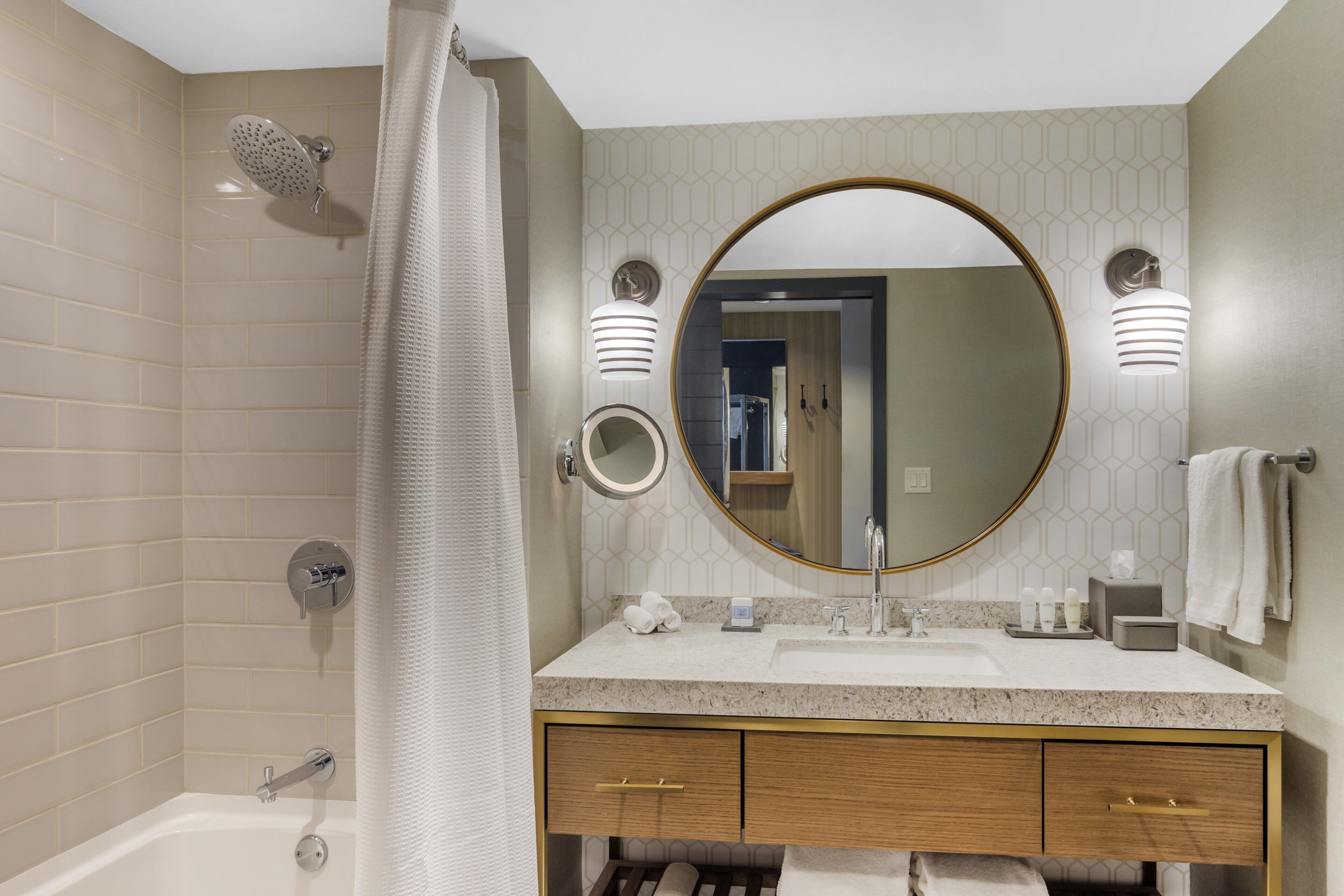 A modern bathroom with a bathtub, a shower, a sink with a vanity, and a large mirror.