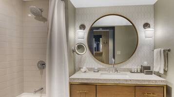 A modern bathroom with a bathtub, a shower, a sink with a vanity, and a large mirror.