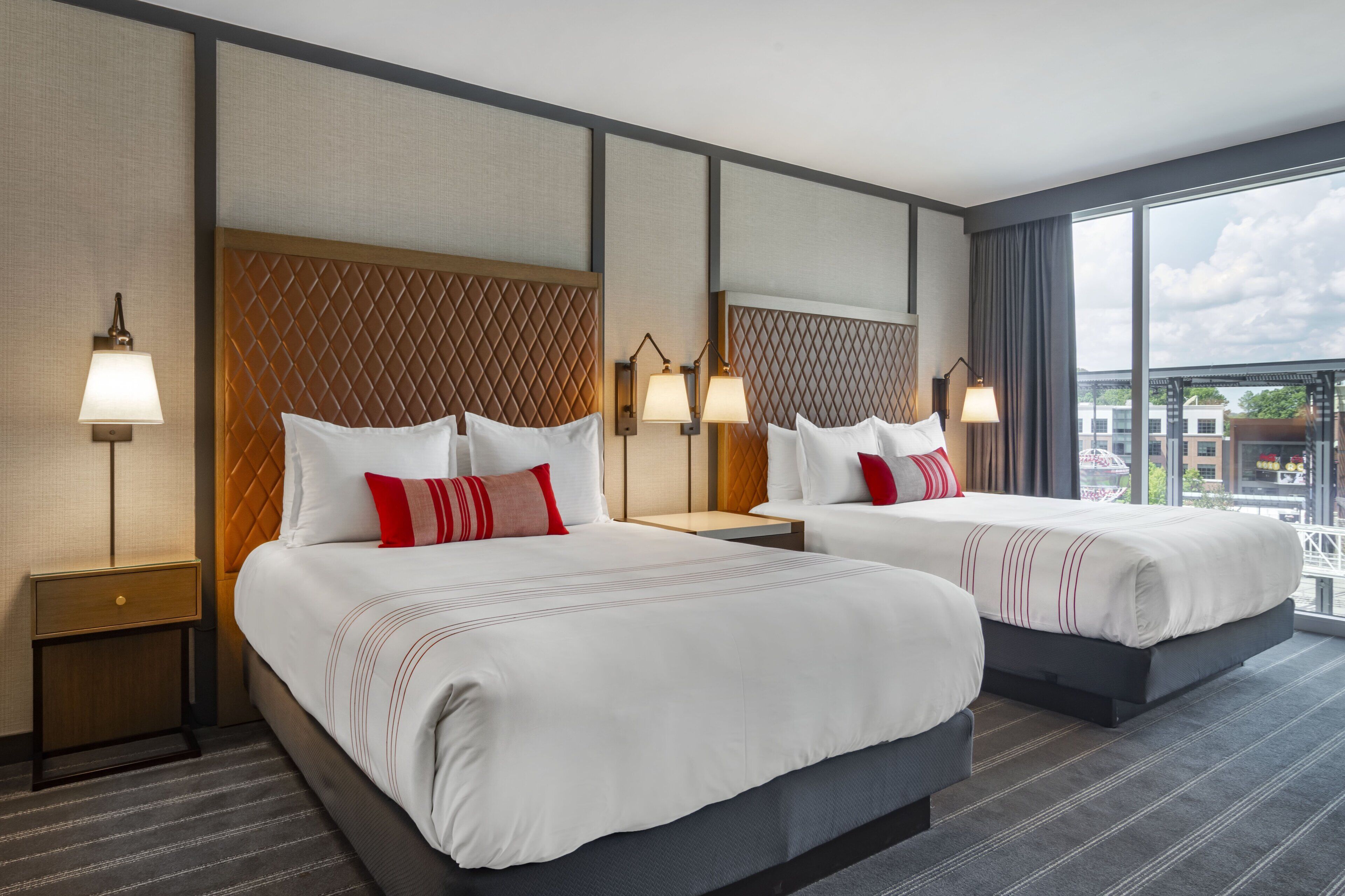 Een hotelkamer met twee bedden, een groot raam en uitzicht op de stad.