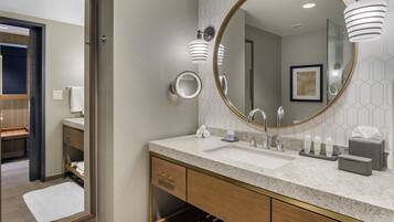 A modern bathroom with a large mirror, two sinks, and a vanity with a towel rack.