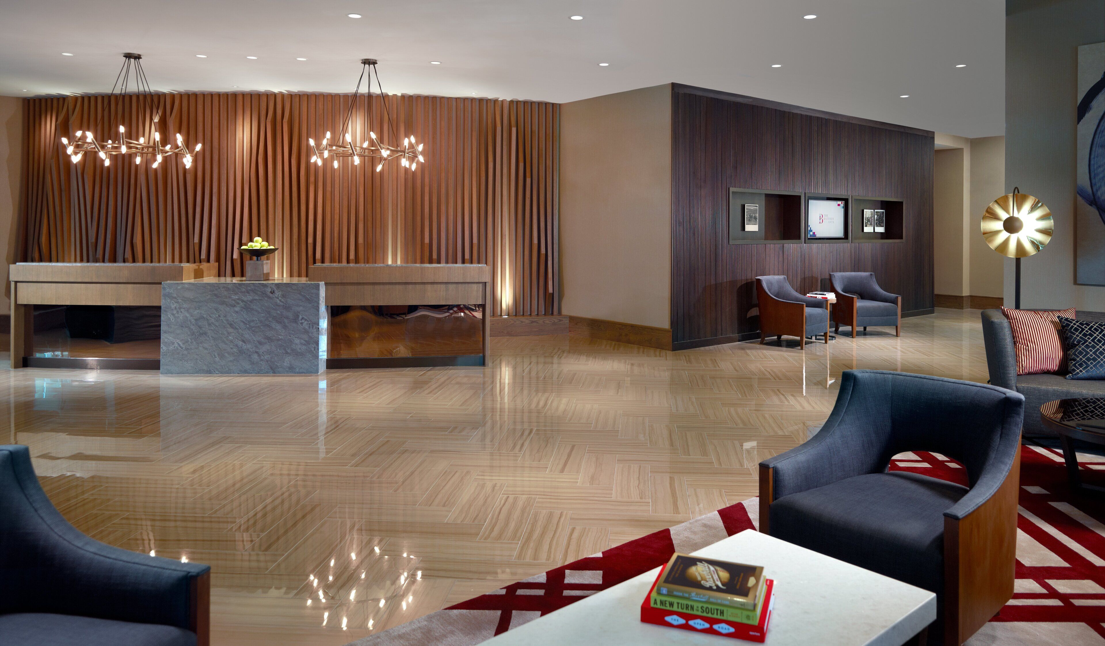 A modern lobby with a reception desk, seating area, and a large chandelier.