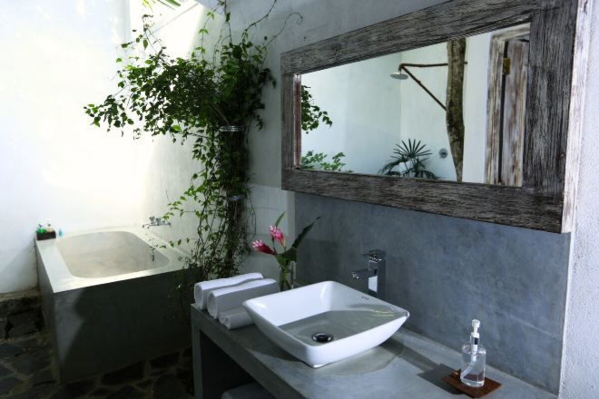 A bathroom with a bathtub, a white sink, and a mirror.