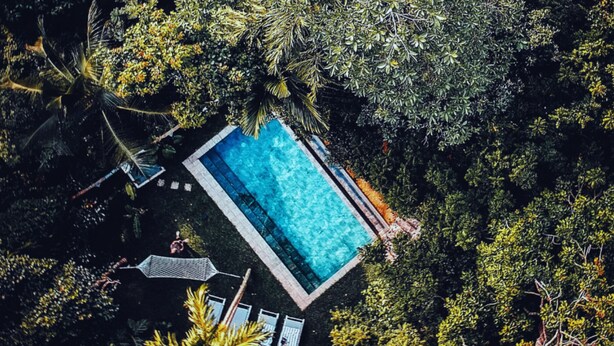 An aerial view of a rectangular pool surrounded by dense foliage, with a clear blue pool and a small deck area. - Ceylon Olive (Galle)