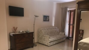 Una sala de estar con un sofá, un televisor montado en la pared, una lámpara de pie y un marco de fotos.