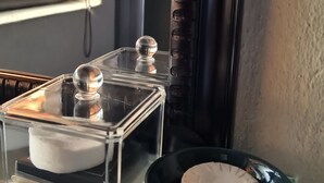 A glass shelf with a clear container holding a white object and a black bowl with a beige object. - The Dreamcatcher Lodge (Hoedspruit)