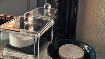 Una estantería de vidrio con un recipiente transparente que contiene un objeto blanco y un tazón negro con un objeto color beige.