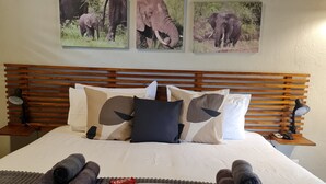 A neatly made bed with a welcome mat, rolled towels, and a welcome card. - The Dreamcatcher Lodge (Hoedspruit)