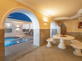 Un área de spa con jacuzzi, asientos y una mesa con un florero y flores.