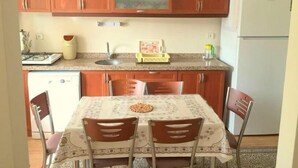 A compact kitchen with wooden cabinets, a sink, and a dining table with chairs.
