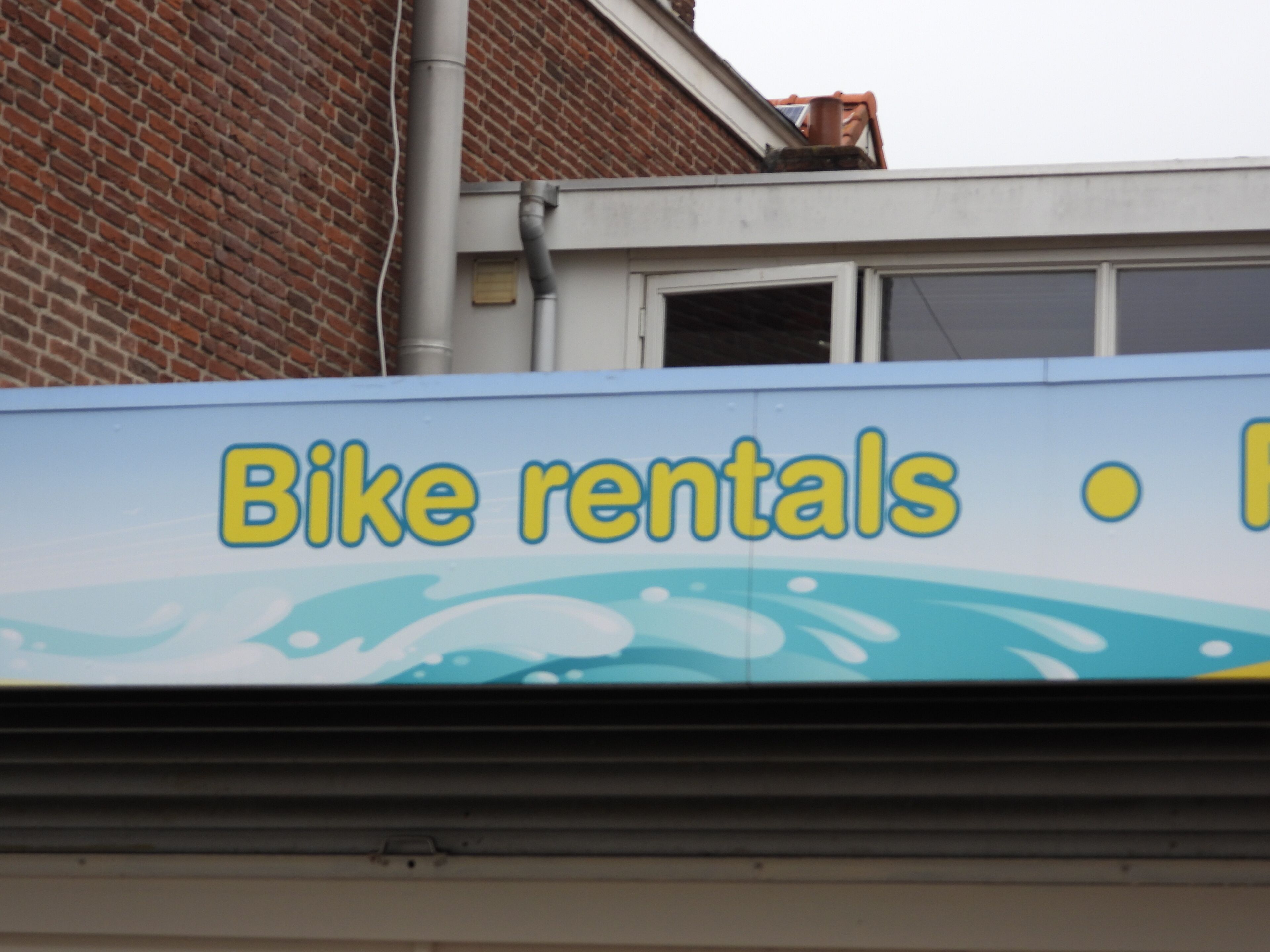 Skilt for cykeludlejning med blå baggrund og gul tekst.