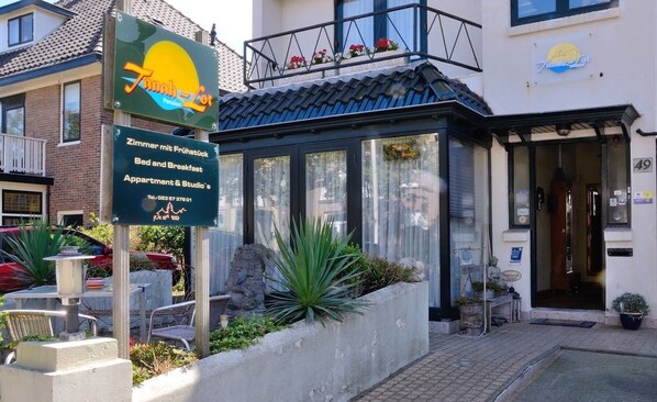 A building with a sign for 'Zimmer mit Frühstück' indicating breakfast included. There is a balcony with flowers and a sign for 'Farn-Lot'. - Pension Villa Tanahlot (Zandvoort)