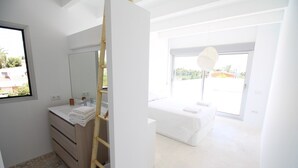 A modern bedroom with a large window, a bedside table, and a wardrobe. - Villa Nathalie (El Campello)