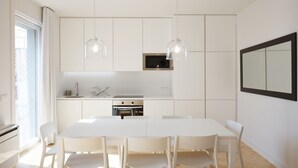 A modern kitchen with white cabinetry, a central island, pendant lights, and a large mirror on the wall. - City Stays Sé Apartments (Lisbon)
