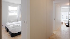 A modern hotel room with a large bed, a wardrobe, and a bathroom visible through an open door. - City Stays Sé Apartments (Lisbon)