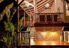 Um deck de madeira em vários níveis, com guarda-corpo, escada e ventilador de teto.