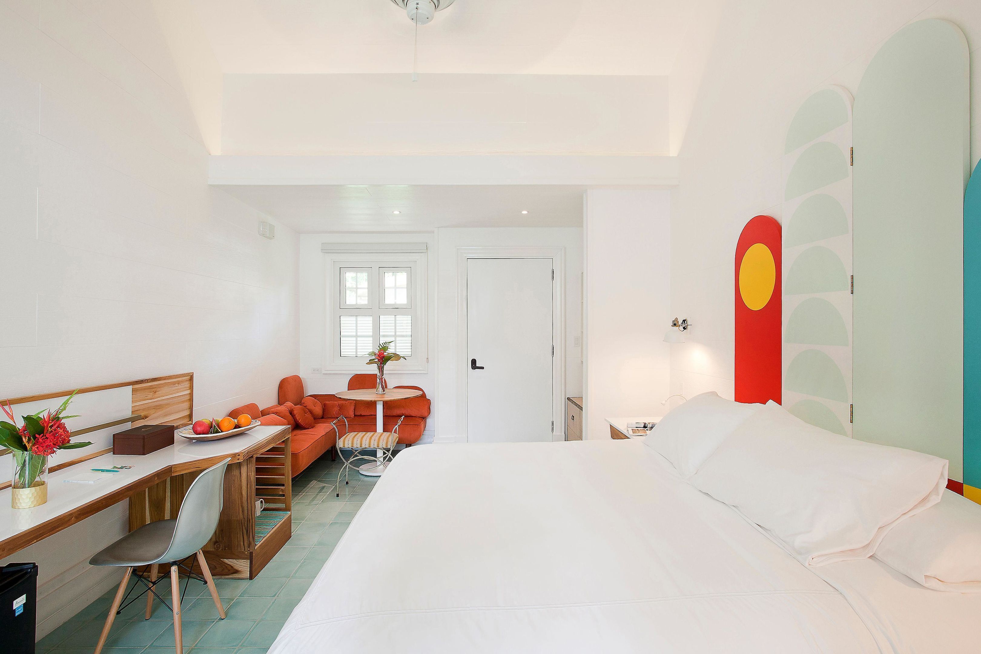 Una habitación de hotel con cama, escritorio con silla, una mesita con otra silla y un sofá.