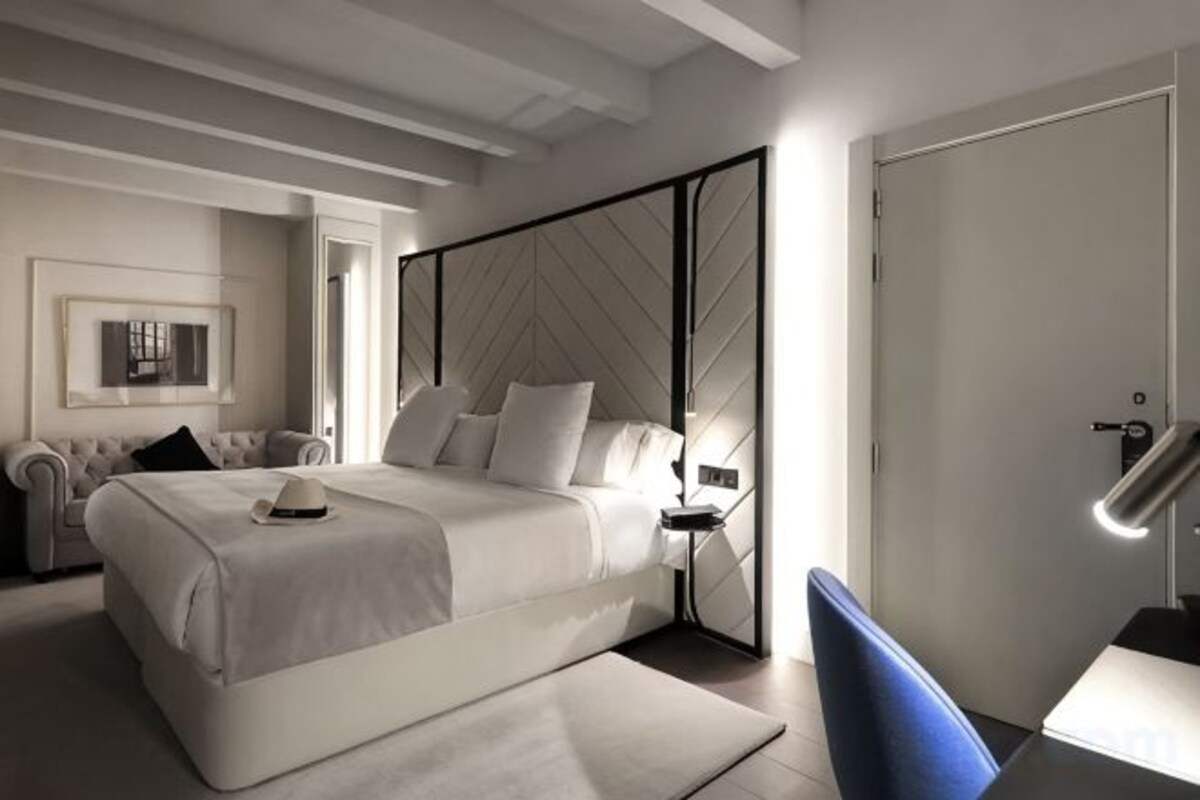 Un dormitorio moderno con una cama grande, mesitas de noche, una silla y un armario.