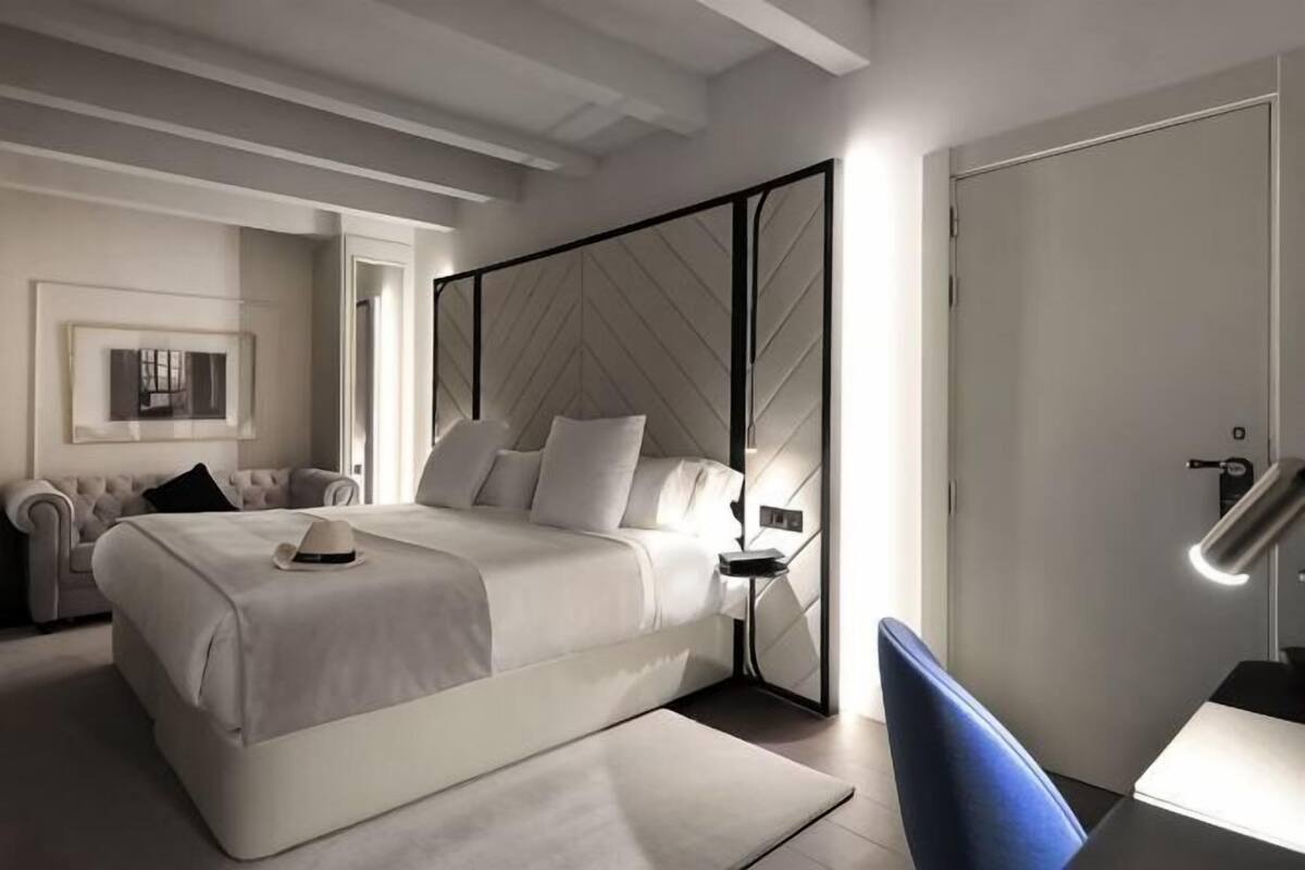 A modern bedroom with a bed, bedside tables, a chair, and a door.