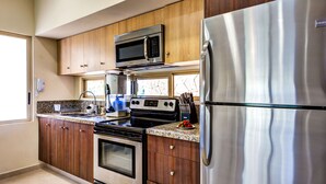 A modern kitchen with wooden cabinets, stainless steel appliances, and a granite countertop.
