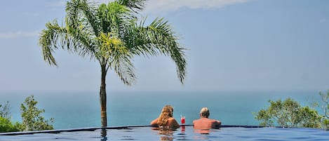 Una piscina al aire libre, sillones reclinables de piscina