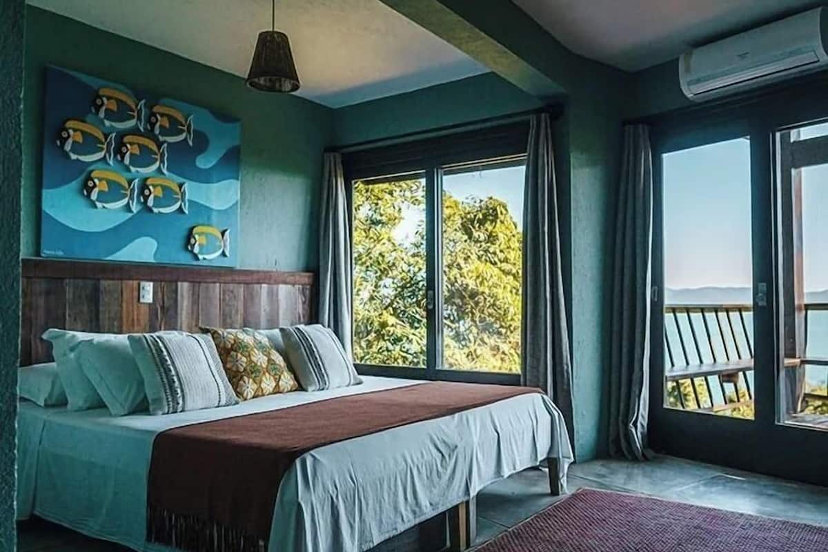 Un dormitorio con una cama grande, vistas al exterior y un cuadro con peces.