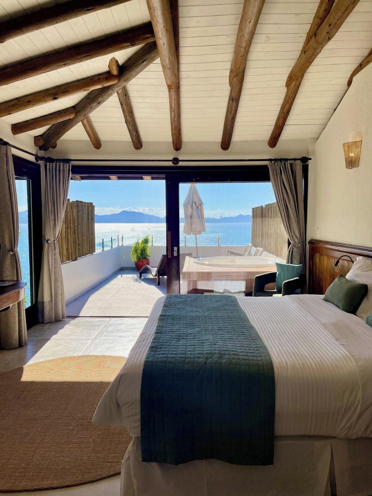 Una habitación de hotel con una cama grande, vista al mar y techo de madera.