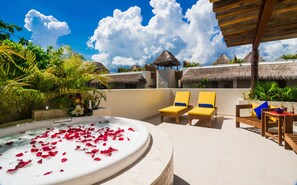 Una terraza en la azotea con jacuzzi, sillones de descanso y vistas a edificios con techos de paja.