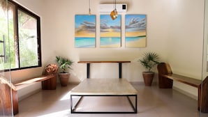 Een kamer met een houten bank, een tafel en potplanten.