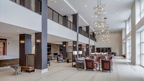 A spacious lobby with high ceilings, modern lighting fixtures, and multiple seating areas. - Hotel Madison & Shenandoah Conference Ctr (Harrisonburg)